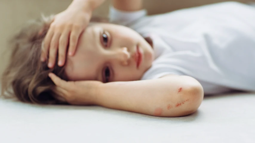 Child lying on the ground holding their head after injury